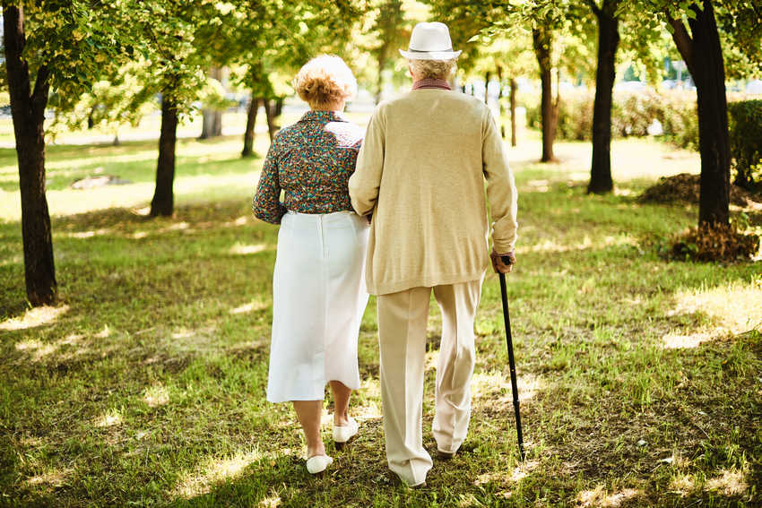 man holding elderly woman while walking